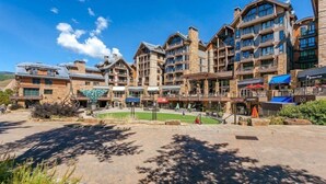 Un hotel de varios pisos con un patio central, asientos al aire libre y montañas al fondo.