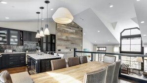 A modern kitchen with dark cabinets, a large island, and pendant lighting. - 5 Bedroom Ski-in/ski-out Luxury Townhome in The Meadows Townhomes (Avon)