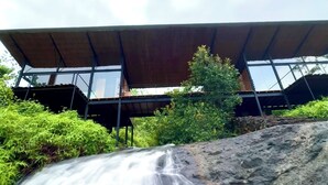 Een modern gebouw met een plat dak en grote ramen, gelegen nabij een waterval.