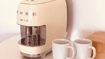 Eine Kaffeemaschine mit zwei weißen Tassen auf einem Holzteller.