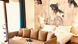 A modern room with a sofa, a bed, and a wall mural of fish. - Il Borgo Boutique rooms By Kasa Vacanze  (Loiri Porto San Paolo)