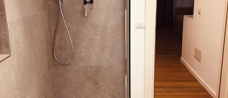 Un baño moderno con ducha, paredes con azulejos y suelo de madera.