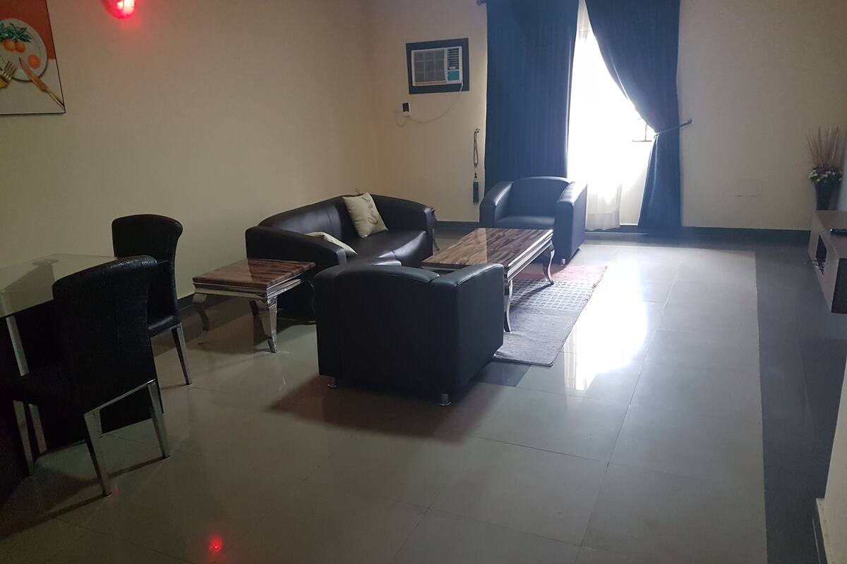 A living room with a sofa, two armchairs, a coffee table, and a dining table with chairs.