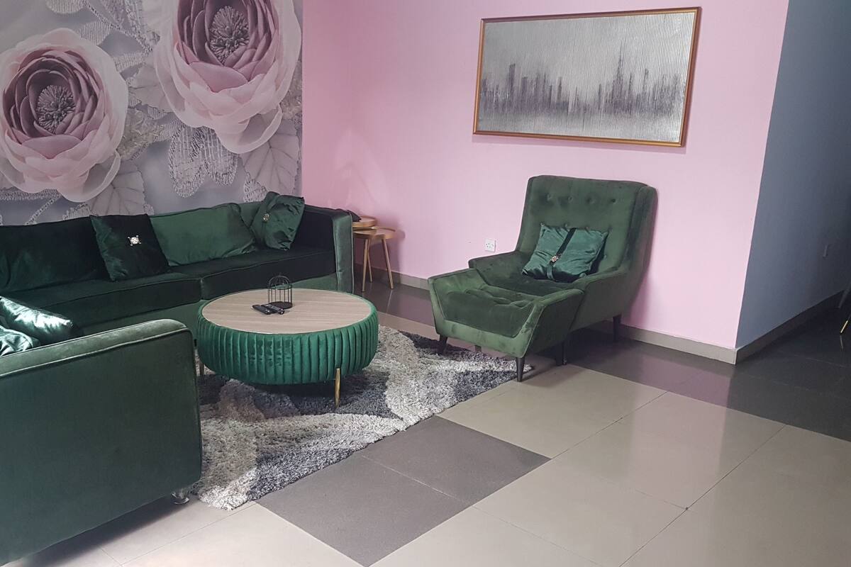 A living room with a green sofa set, a round coffee table, and a green armchair.