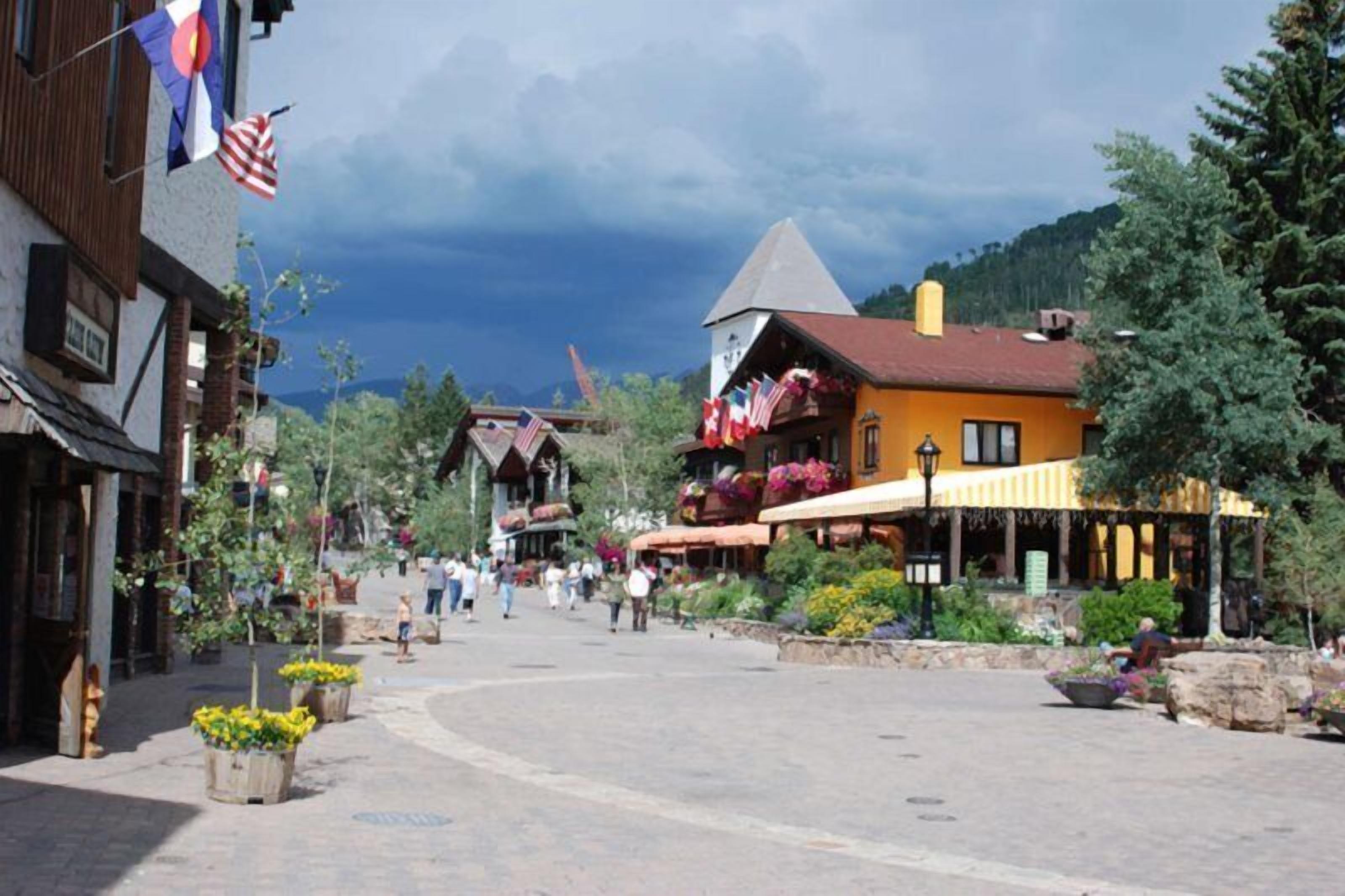 A town square with buildings, including a yellow building with a red roof and a white building with a brown roof.