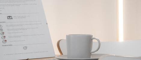 Una mesa con un menú, una taza y una silla.