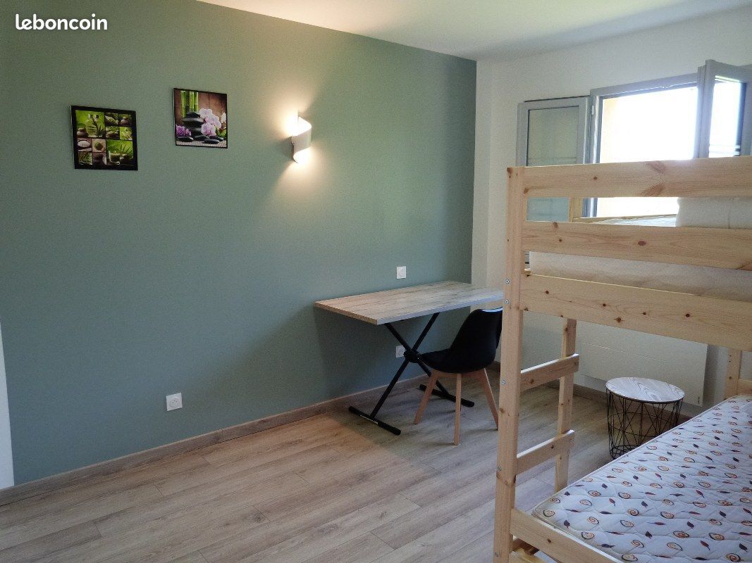 Een kamer met een stapelbed, een bureau met stoel en twee wandlampen.