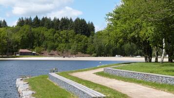 Ein Park am Seeufer mit einem Kiesweg, Rasenflächen und einem Strand in der Ferne.