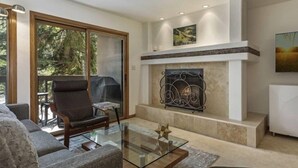 A modern living room with a glass coffee table, a fireplace, and a painting on the wall. - Townsend Place 2 Bedroom Ski-in, Ski-out Condo in Beaver Creek Village (Avon)