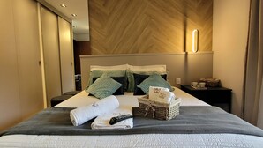 A neatly made bed with towels, a remote control, and a basket with a note. - Dúplex Luxo com Piscina Aquecida, Lareira e Wifi (Campos do Jordão)