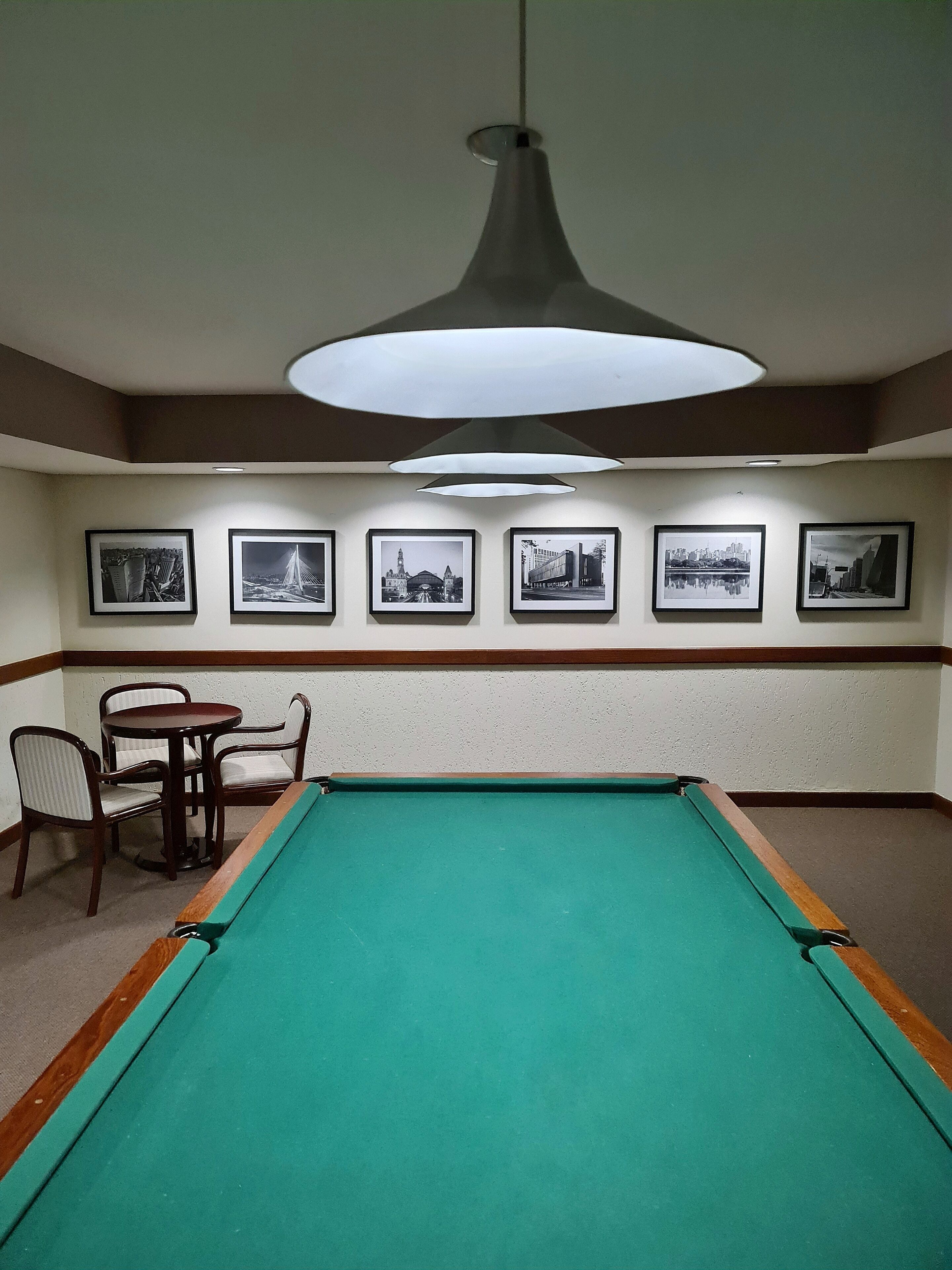 Una mesa de billar con seis fotografías enmarcadas en la pared.