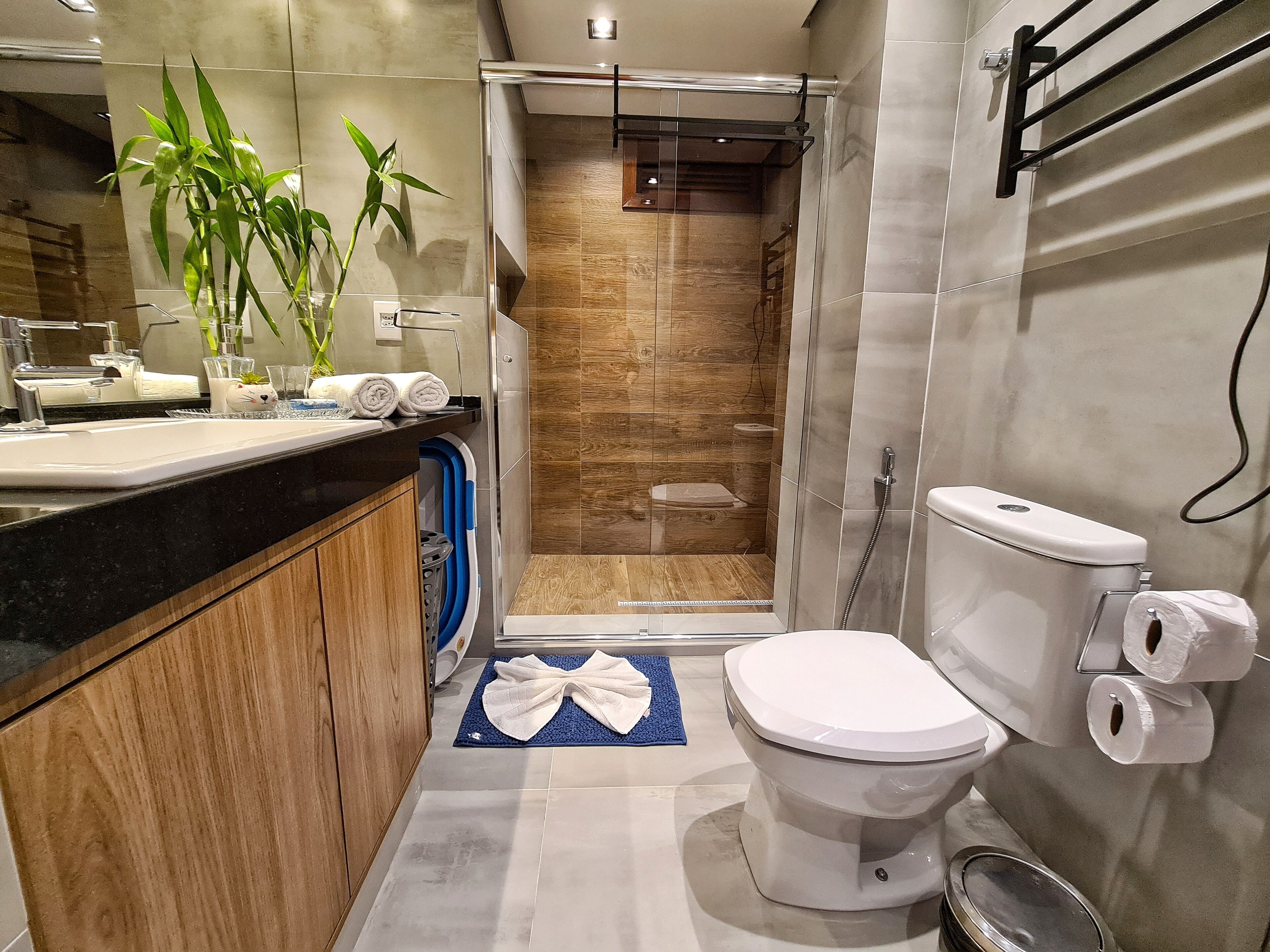 Un baño moderno con tocador de madera, cabina de ducha de vidrio y un inodoro con toallero.