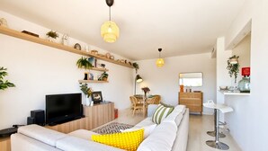 A modern living room with a sofa, TV, and shelves with decorative items.