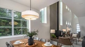 A dining area with a wooden table, white plates, and a hanging light fixture. - Black Diamond Cabin | Private Hot Tub • Wood Fireplace • BBQ (Agassiz)