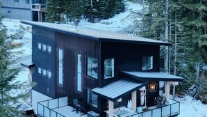A modern two-story cabin with a balcony, a hot tub, and a fireplace. - Black Diamond Cabin | Private Hot Tub • Wood Fireplace • BBQ (Agassiz)