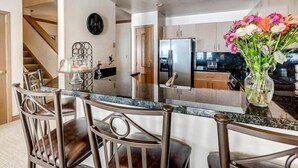 A modern kitchen with a central island, stainless steel appliances, and a vase of flowers on the counter.