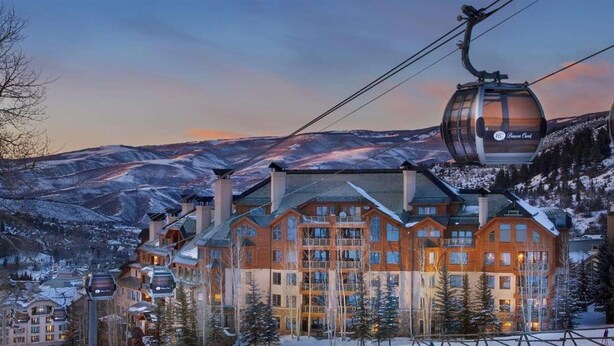 A ski resort with a large lodge, ski lifts, and snow-covered mountains in the background.