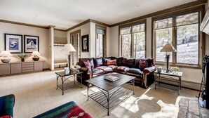 A spacious living room with a leather sofa, a coffee table, and a large window providing a view of the outdoors.