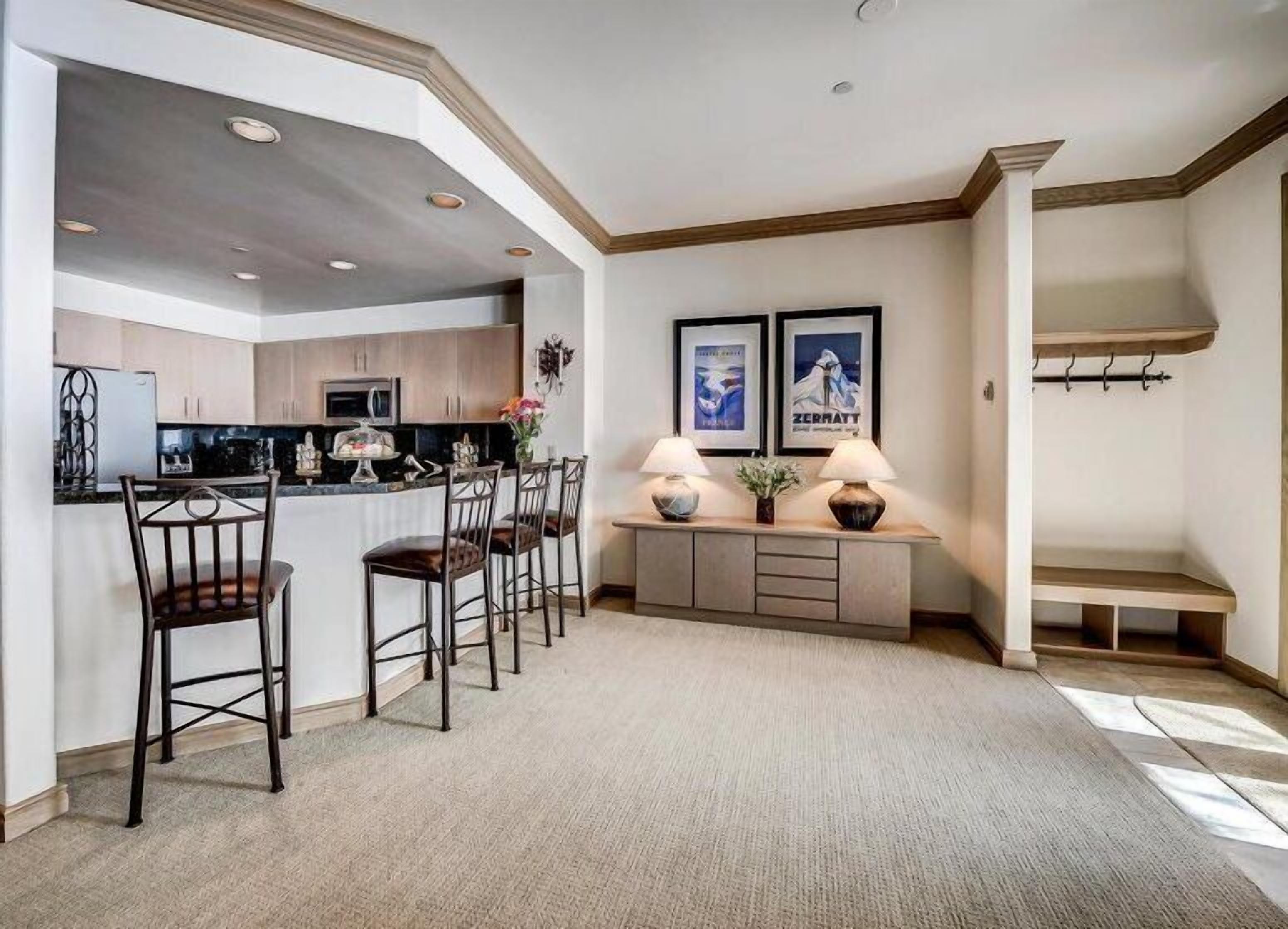 A modern kitchen with a central island, bar stools, and a dining area with a bench.