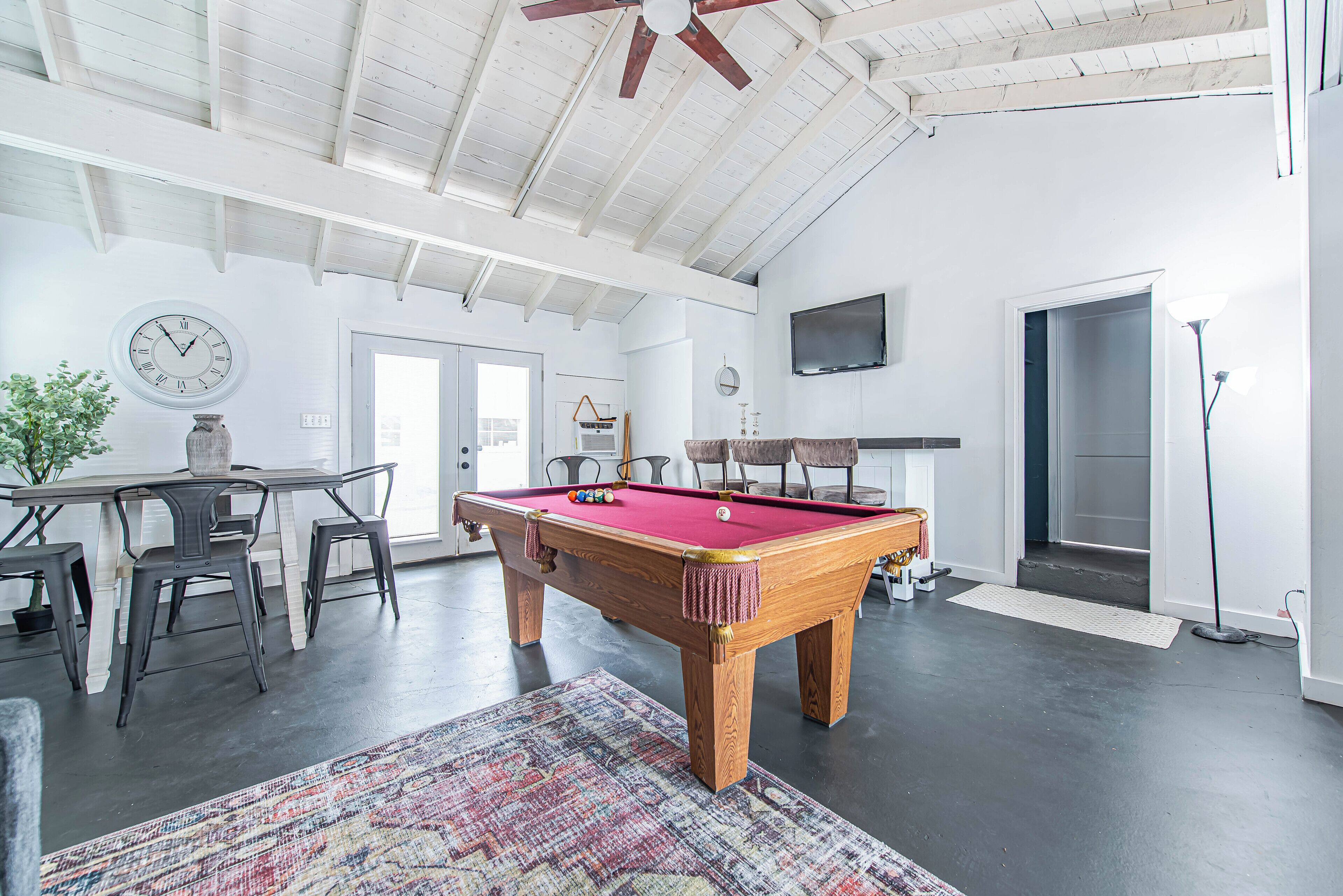 Una habitación amplia con mesa de billar, comedor con sillas y ventilador de techo.
