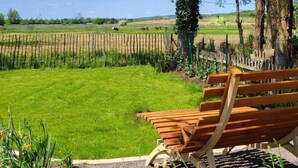 A wooden bench in a park with a view of a field and trees.