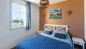 A bedroom with a bed, a window with curtains, a wall-mounted picture, and a bedside table. - La Cabre d'Or - Duplex climatisé (Cabriès)