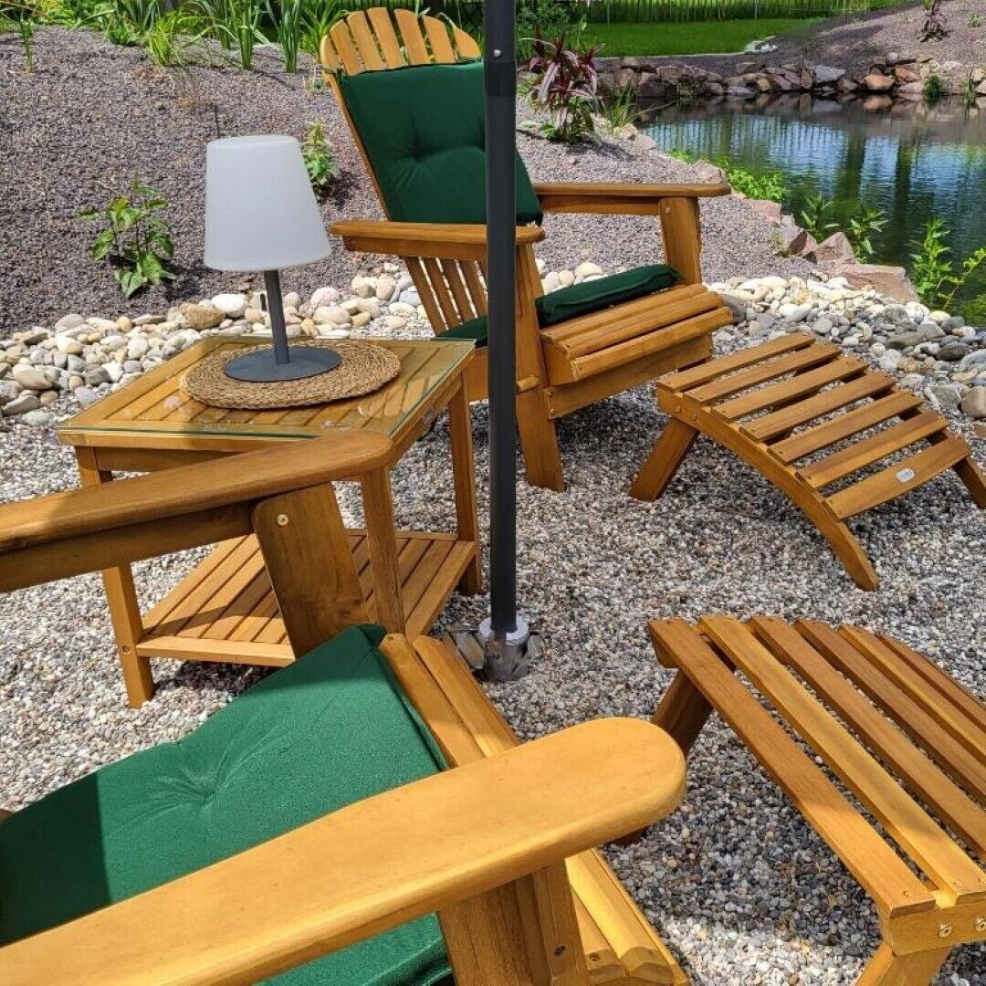 A wooden outdoor seating area with a table and chairs, a lamp, and a small pond in the background.