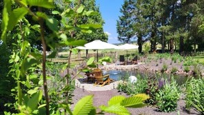 A garden with a pond, seating area, and trees. - Gästehaus am Bachlauf - Losheim am See 
Wohnung 6 – Weitblick (Losheim am See)