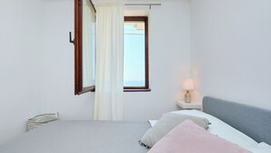 Une chambre à coucher avec un lit, une table de chevet, une lampe, une fenêtre avec des rideaux et une vue sur le ciel.