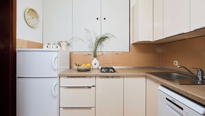 Une cuisine avec des armoires blanches, un réfrigérateur blanc, un évier et une cuisinière.