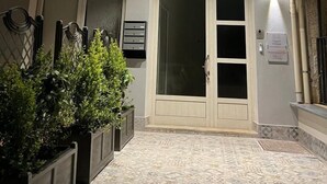 Een gebouw met twee verdiepingen, een balkon, een grote gewelfde deuropening en een betegelde binnenplaats.