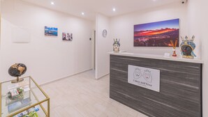 Een receptiegedeelte met een modern design, met een receptiebalie, ingelijste kunstwerken aan de muur en een wereldbol op een glazen tafel.