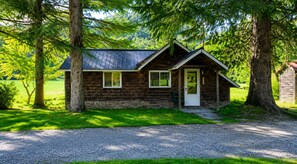 A rustic cabin with a sloped roof, a front porch, and a gravel driveway. - Cold Spring Lodge - Cabin 2 (Big Indian)
