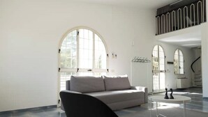 Ein geräumiges Wohnzimmer mit grauem Sofa, einem Couchtisch und einer Treppe, die in eine obere Etage führt.