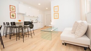 Una sala de estar moderna con una mesa de centro de vidrio, un sofá blanco y un comedor con sillas y una mesa.
