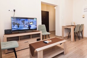 Relax in a spacious living area with a flat-screen TV, comfortable seating, and a dining table for a convenient stay.