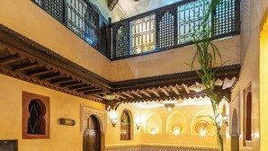 A spacious courtyard with a high ceiling, a seating area with sofas and a coffee table, and a dining area with chairs and a table.