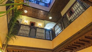 An interior view of a building with ornate balconies, decorative lighting, and a view of the sky through a window.