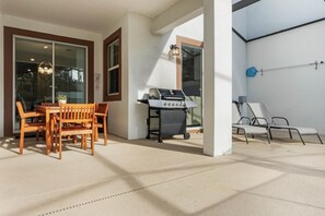 Enjoy al fresco dining and relaxation in this patio area, featuring a dining table, barbecue grill, and lounge chairs.