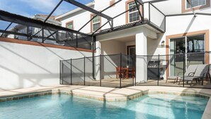 Una piscina con sombrilla, mobiliario exterior y zona de barbacoa.