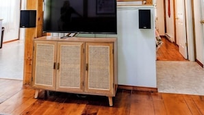 A living room with a wooden TV stand, a flat-screen TV, and two speakers.
