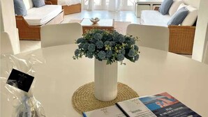 Una habitación moderna y bien iluminada con una mesa de comedor, sillas, un jarrón de flores y un menú.