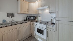 A modern kitchen with light wood cabinets, a granite countertop, a built-in oven, a microwave, a toaster, and a coffee maker. - Central 1 BR apartment in Birmingham (Birmingham)