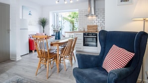 Una cucina moderna con forno integrato e zona pranzo con sedie e tavolo in legno.