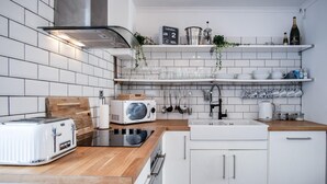 Una cucina moderna con mobili bianchi, un piano di lavoro in legno, un forno a microonde integrato, un tostapane e un lavello.