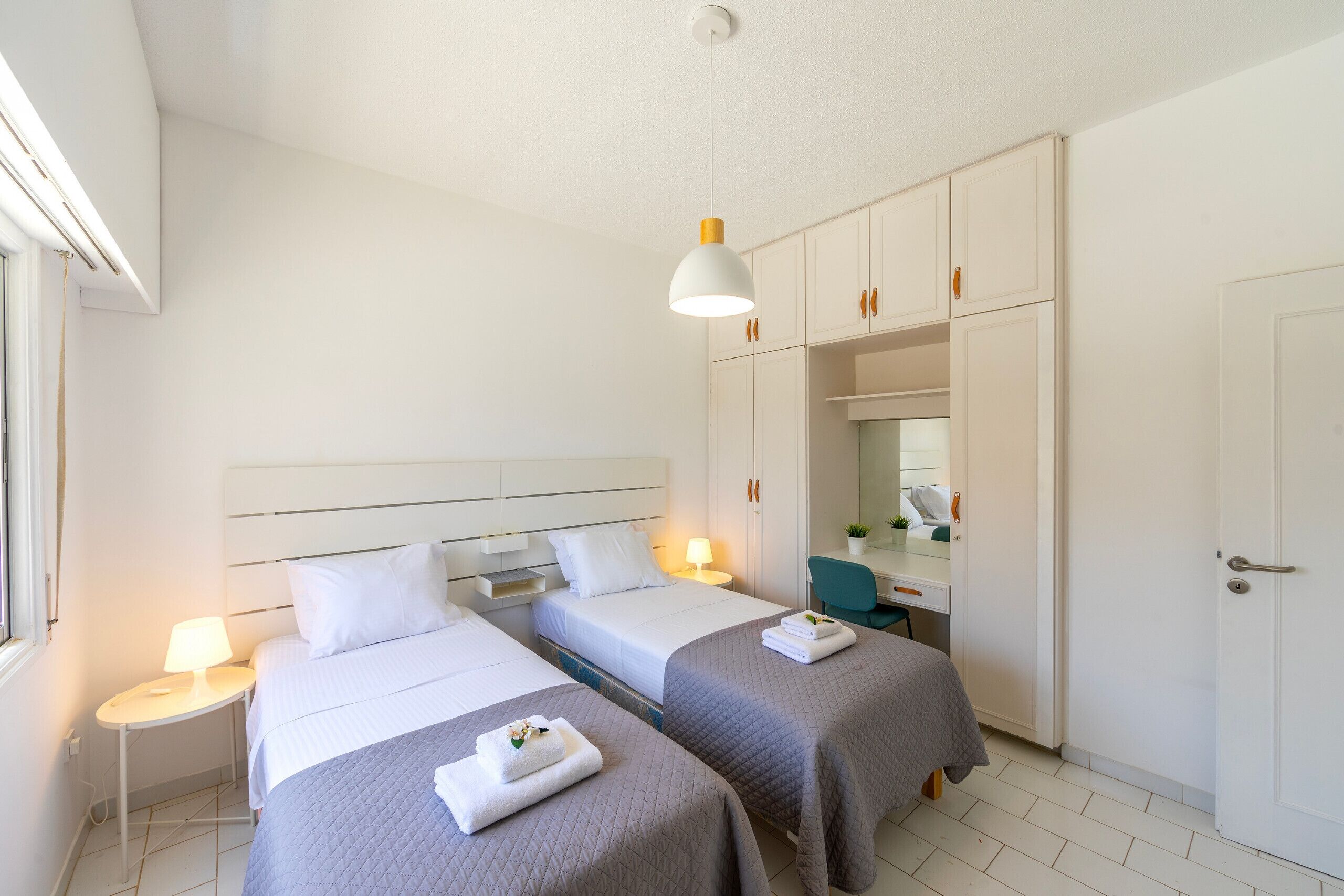 Une chambre d’hôtel avec deux lits, un bureau, une armoire et une salle de bain.
