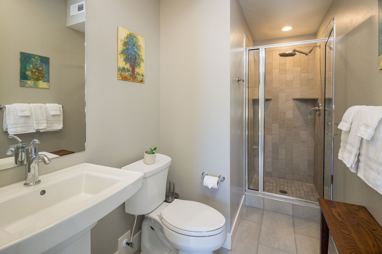 Een moderne badkamer met een douchecabine van glas, een witte wastafel en een toilet.
