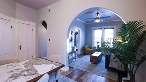 Una habitación amplia con una mesa de comedor, una planta grande en maceta y un ventilador de techo.