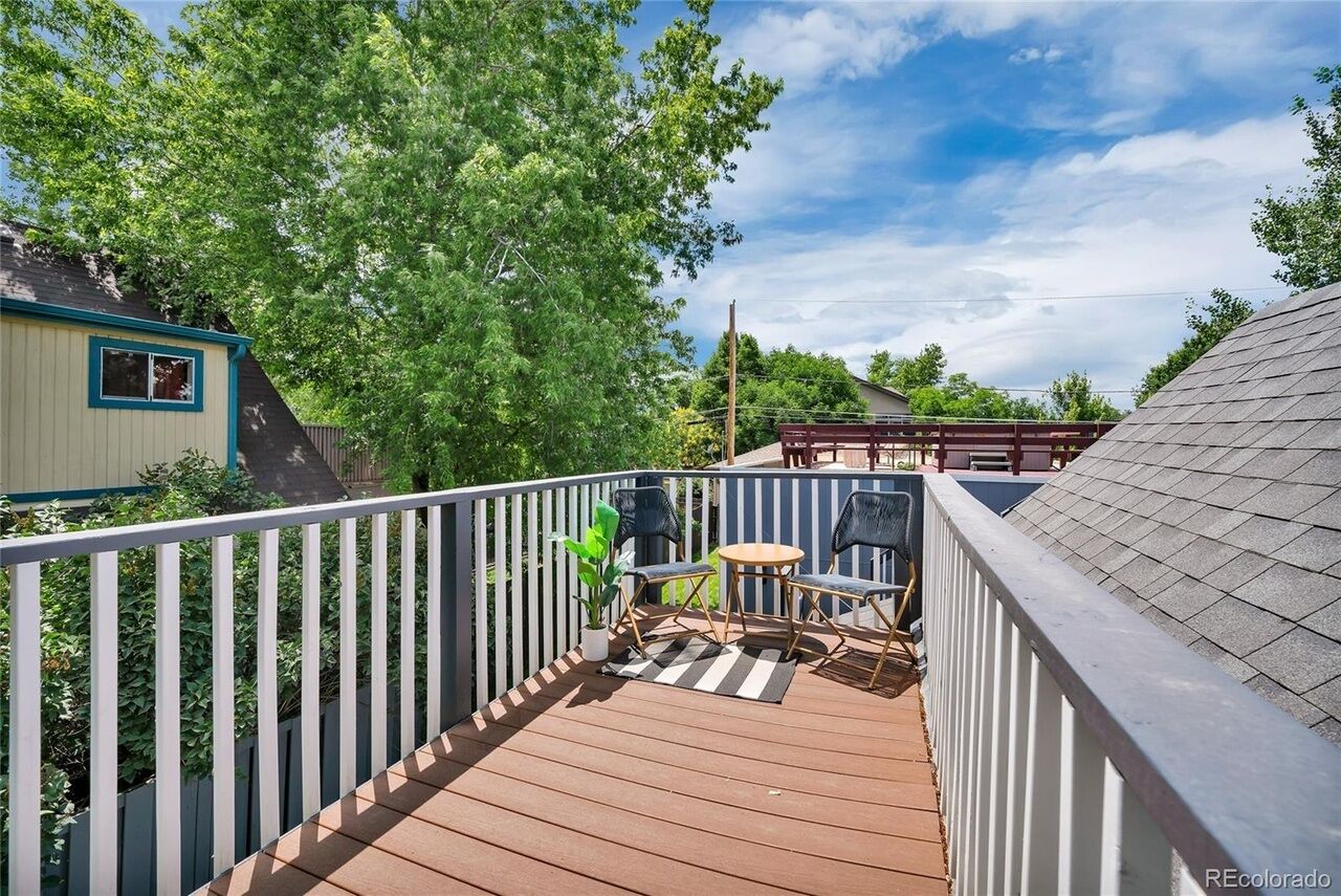 A wooden deck with a railing, a small table, and two chairs.
