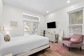 Une chambre à coucher avec un lit, une chaise, un téléviseur et une fenêtre avec des stores.